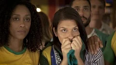 Brazilian football fans looking disappointed while watching televised match in