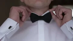 The man hands are correcting the black bow-tie and getting ready to the wedding.