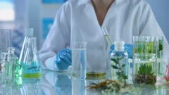 Female chemist pouring cosmetic oil in test liquid, body care production, aroma