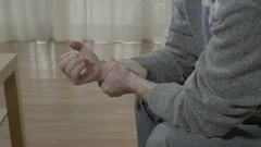 Closeup of old man with arthritis touching his painful wrist having rheumatis