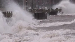 Wind driven waves crash into shore in typhoon and hurricane force wind storm