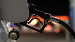 Fuel nozzle inserted in car's gas tank being refueled at gas station pump