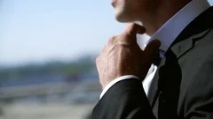 Slow motion. Man straightens bow-tie close up