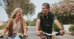 Happy senior couple riding bikes in suburban street in spring