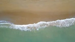 Aerial view of looping ocean wave reaching the coastline. Summer tropical beach