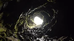Arnarker cave lava tube Iceland, moss covered wet rocks, looking out entrance