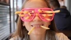 4 Kid girl face portrait in party glasses with funny sticking french fries in