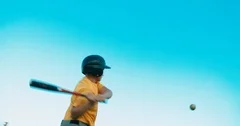 LOW ANGLE kid boy batter baseball player hits a ball against blue sky