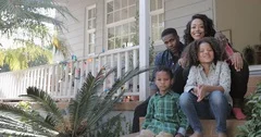 Portrait of African American family sitting outside home
