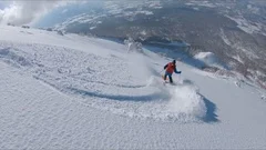 AERIAL: Flying along the male tourist skiing downhill in the scenic backcountry.