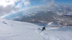 AERIAL: Man shredding the snowy mountain terrain while on fun ski trip in Japan.