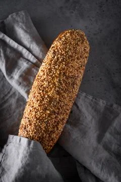 1 loaf of rye grain bread with grains with a gray napkin on a gray background Stock Photos