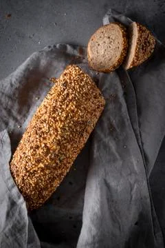 1 loaf of rye grain bread with cut pieces with a gray napkin on a gray backgr Foto stock