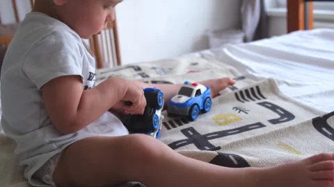 A 1 or 2 year old child plays with a screwdriver and toy police car in car Stock Footage 274470730