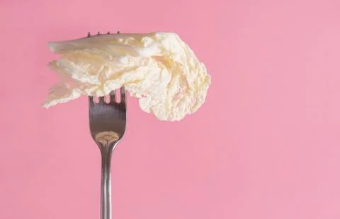 1 white lettuce leaf on a fork on a green background Foto stock