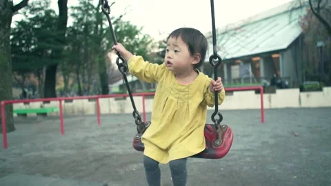1 year old and four-year-old kid playing in a swing on a holiday Video stock 161858403