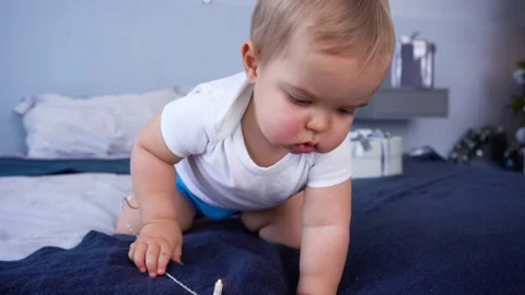 1 year old baby boy plays with garland. New Year Eve and Merry Christmas holiday Stock Footage 258968919