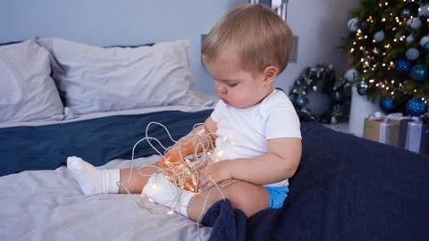 1 year old baby boy plays with garland. New Year Eve and Merry Christmas holiday Stock Footage 258969082