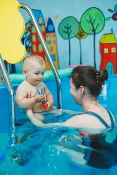 A 1-year-old boy learns to swim in a children's pool with a coach. Swimming c Foto stock