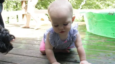 1 year old crawls on wet porch and sticks out her lips Stock Footage 40029092