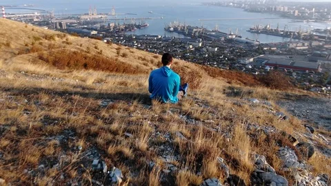 1 young man sitting on a mountain, demonstration dolly zoom effect. Shooting Stock Footage 116780938