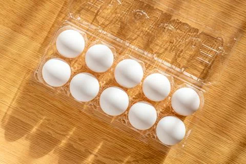10 raw eggs in a clear plastic container Stock Photos