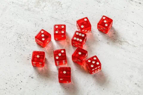 10 translucent red dices on white concrete board. Stock Photos