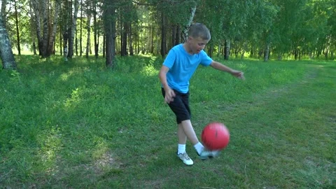 A 10-year-old boy plays with a ball in a clearing in the park. Street football Stock Footage 157814043