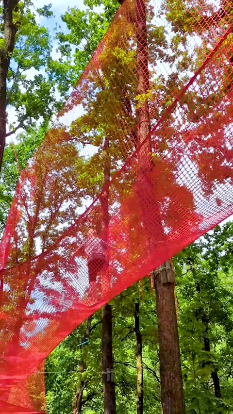 A 10 year old boy plays in an outdoor net park, climbing a mesh maze and jumping Stock Footage 343617181