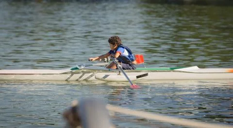 10 year old boy training rowing in a lake near his home with blue life jack.. Stock Photos
