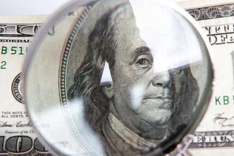 100 US Dollar banknotes under magnifying glass. The concept of business: hund Stock Photos