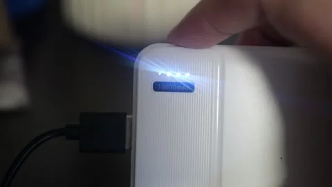 10000mAh power bank connected device user pressing button check remaining charge Stock Footage 320898089
