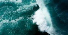 Top down aerial view of giant ocean waves crashing on sunny day