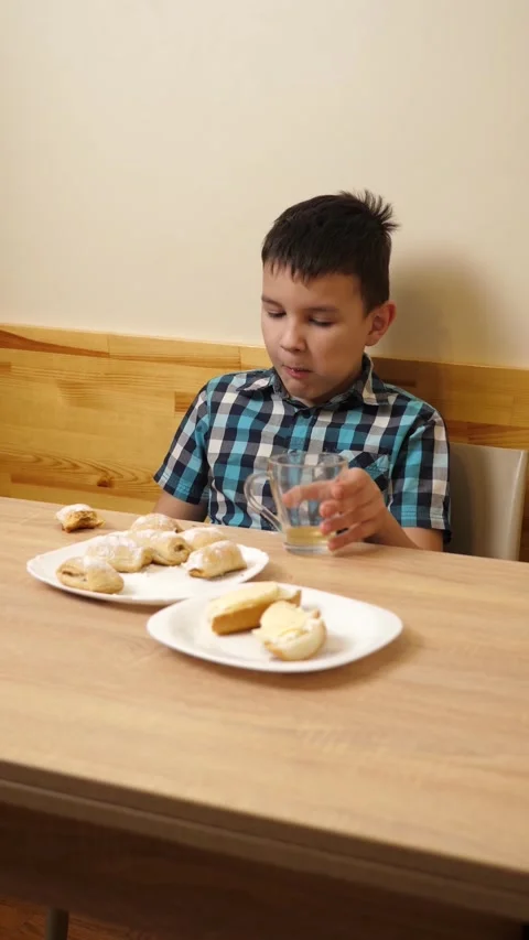 100A boy eats cookies and drinks tea while sitting at the table. Stock Footage 313598766