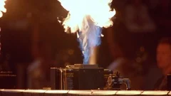 Pyro flame shoots up in front of fans while football players run in the stadium