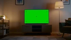 Zoom In Shot of a TV with Horizontal Green Screen Mock Up. Evening Living Room