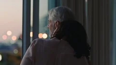 happy couple hugging at home looking out window at sunset enjoying successful