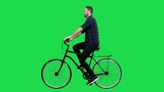 A Cute man riding a bicycle over a green screen, looking around and upwards.
