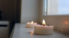 Two white candles burning inside near the window in a Rustic Style Candle Burns