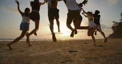 SLOW MOTION - Group of friends running on the beach at sunset with happy emotion
