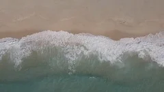Drone footage above waves and sand