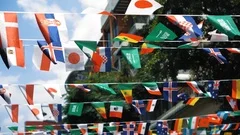Flags of different countries are hung in the air above the street. The world