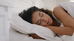 beautiful mixed race woman waking up in bed after restful sleep smiling happy