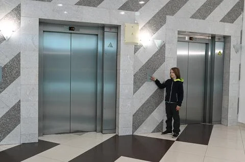 11 year old boy pressing an elevator button in a modern building lobby with Foto stock