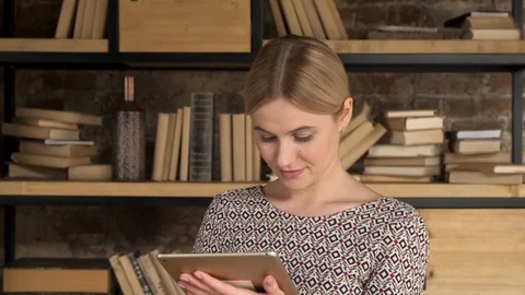 111Good Looking Woman Using A Tablet near bookshelf. Girl touch computer Stock Footage 120009683