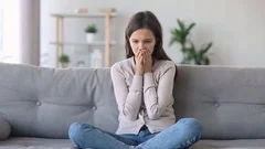 Woman sitting on couch feels nervous caused by personal problems