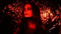 Girl in the form of a devil with horns. Image of halloween in red light. Contact