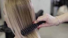 Blonde woman in beauty salon. Hairdresser stylist makes girl's hair.