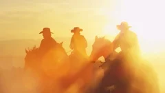 Cowboys riding into the golden sunset at dusk