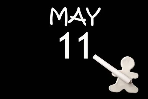 11th day of May. A small white plasticine man writing the date 11 May on a bl Stock Photos